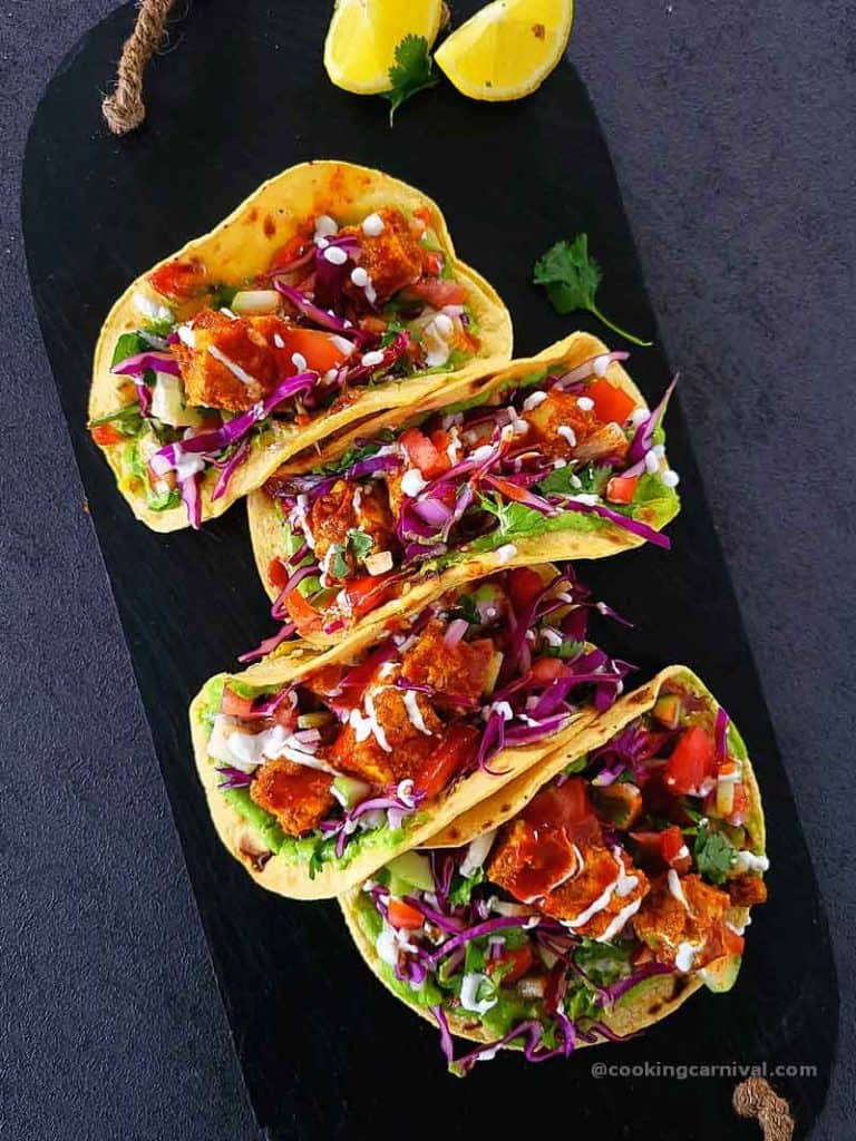 Achari paneer tacos on a black cheese board