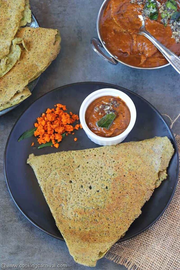 Pesarattu, allam pachadi and peanut powder on a black plate