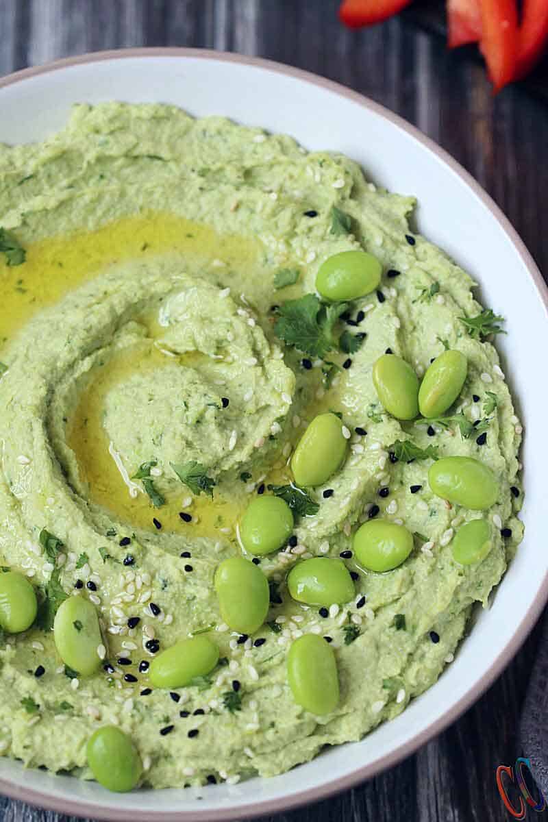 Healthy vegan dip with Black and white sesame seeds, garnished with parsley, served in white bowl.