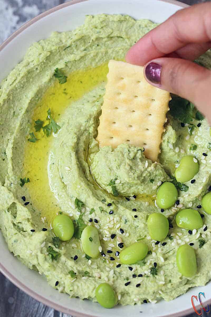 Avocado edamame hummus in a bowl with cracker