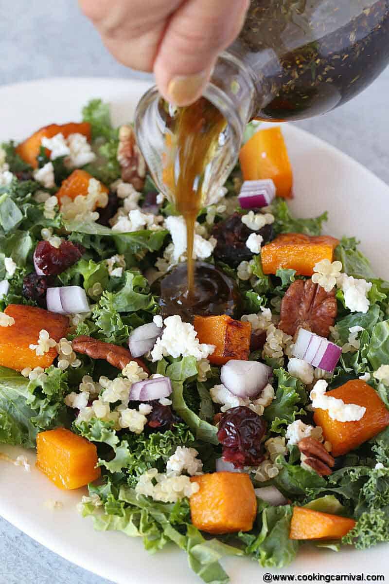 Pouring salad dressing in a roasted butternut squash and quinoa salad