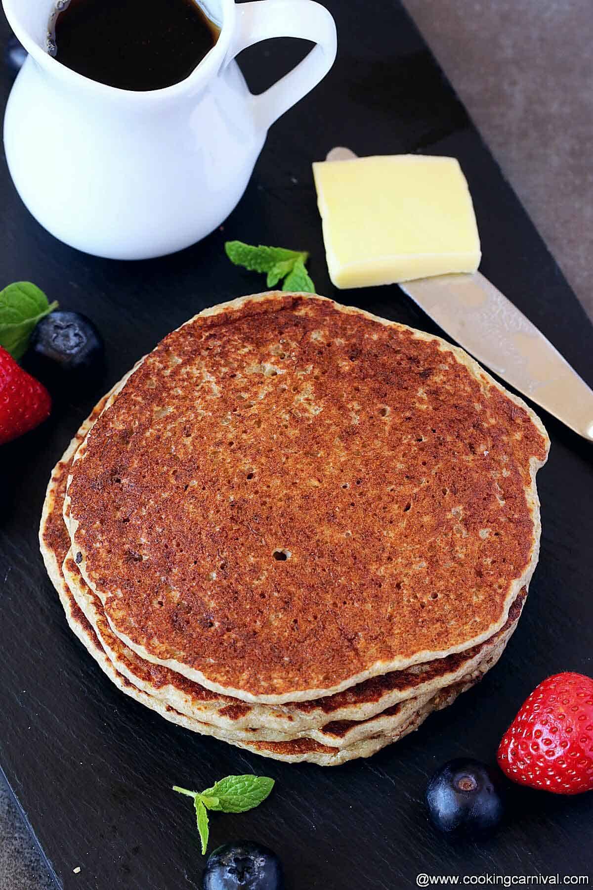 stack of Oatmeal pancake, butter and maple syrup on the sides