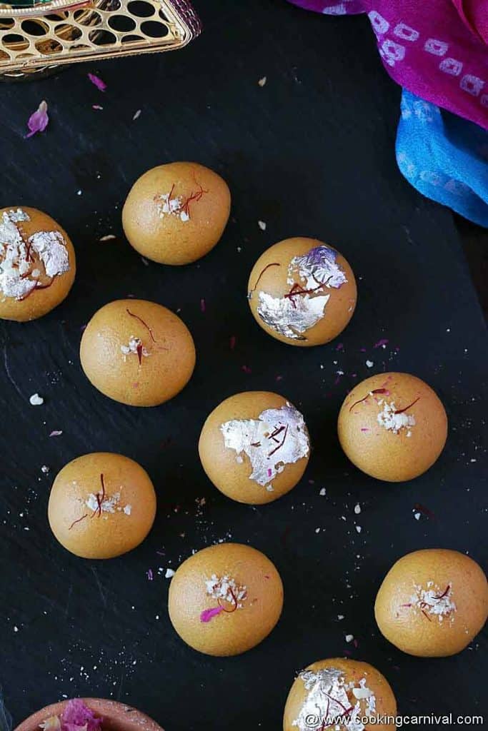 Besan laddu on a black cheese board, captured from top angle