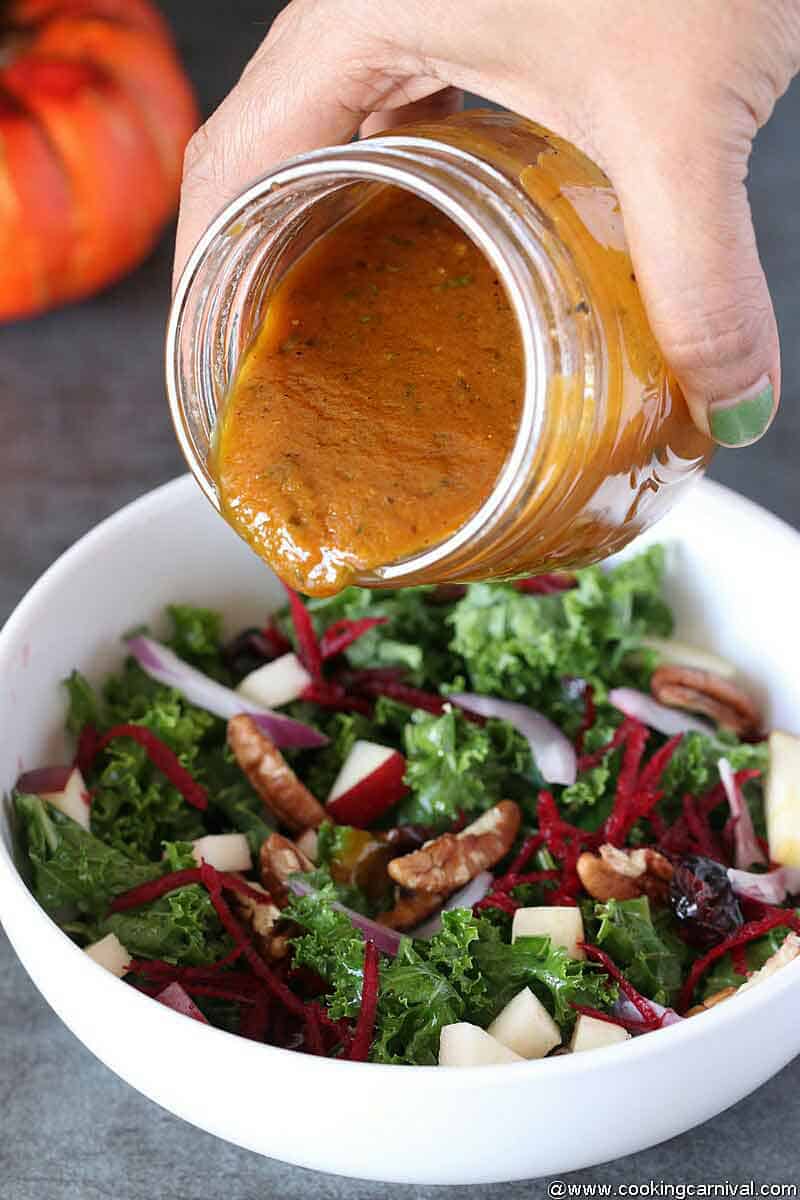 Pouring best Pumpkin Vinaigrette in autumn salad