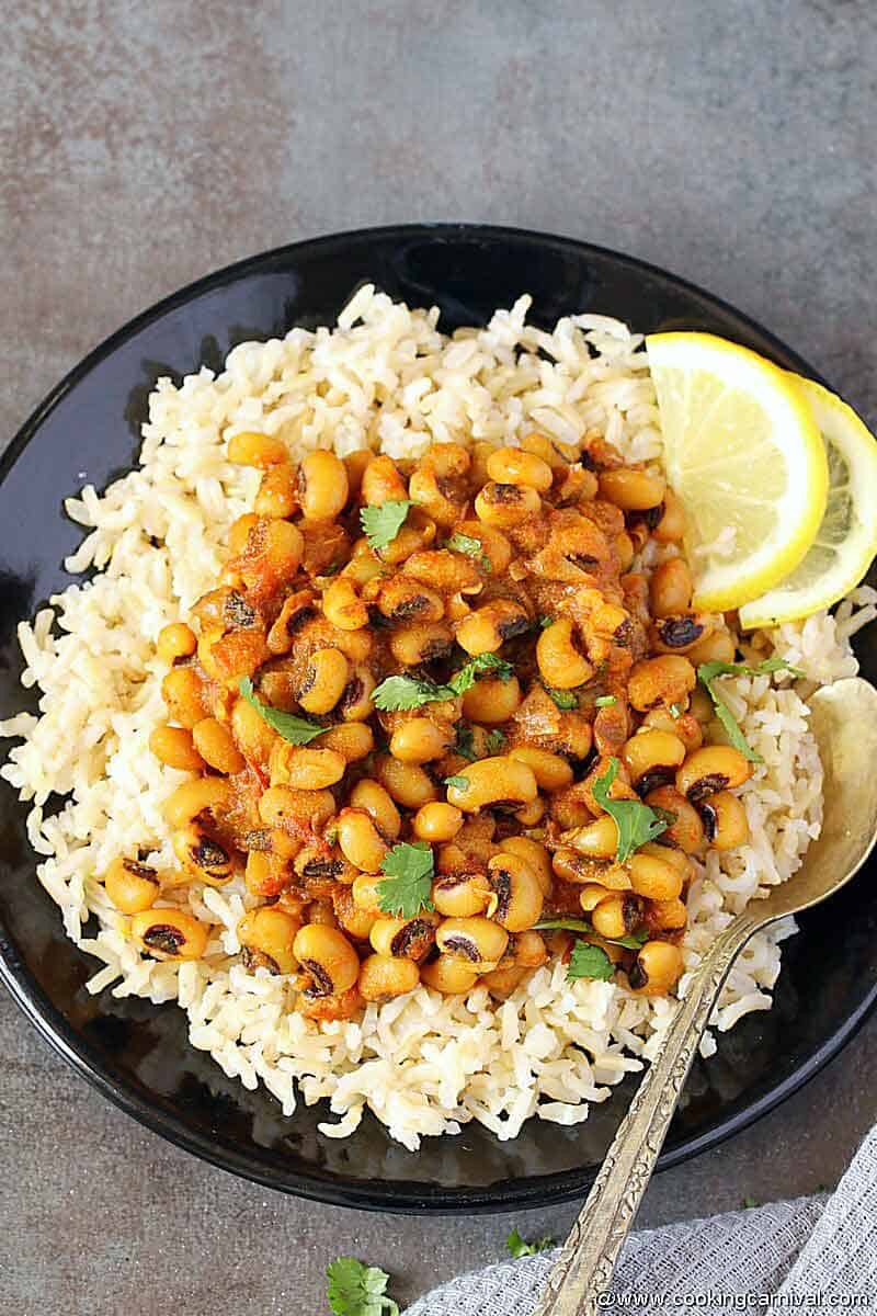 Brown rice and lobia beans curry served in a black plate with a fork