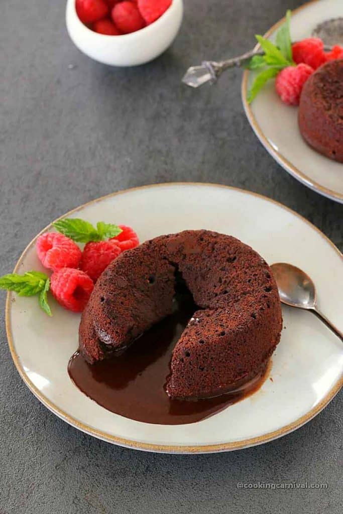 Lava chocolate cake in a plate, berries, mint and spoon on side