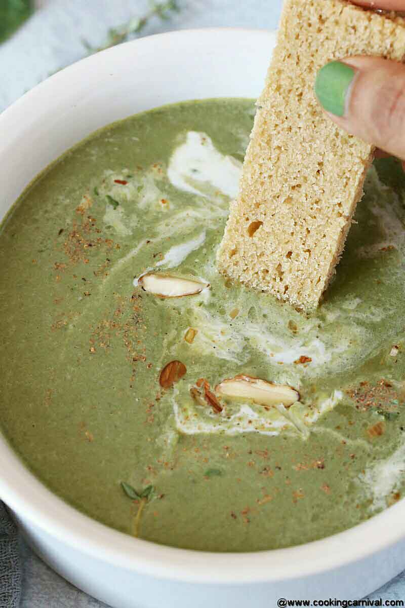 Bowl full of green soup with bread slice