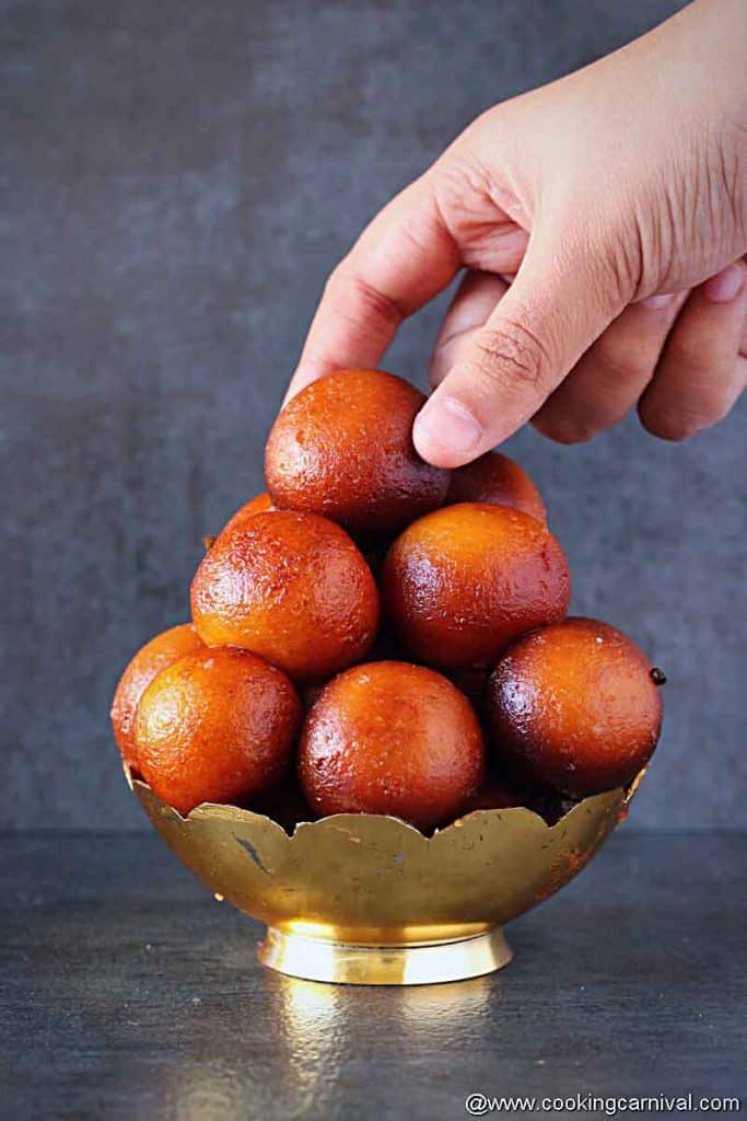 Picking up gulab jamun from the bowl