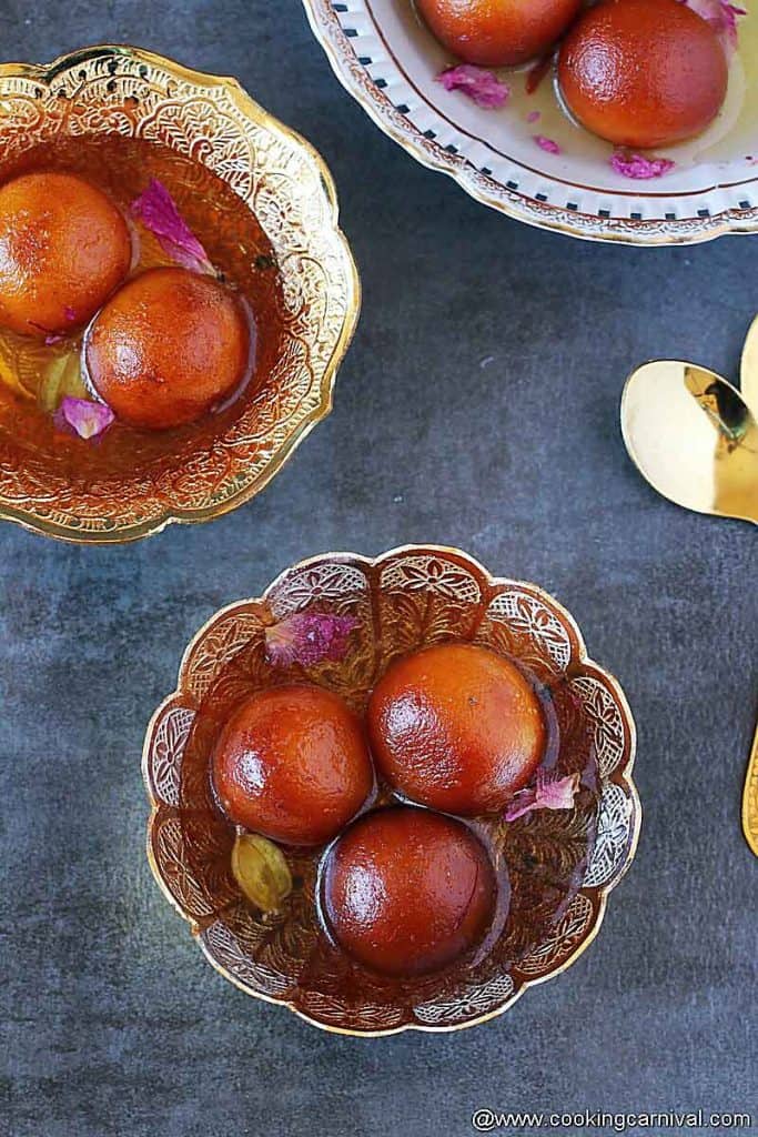 Gulab jamuns in bowls, spoons on the side