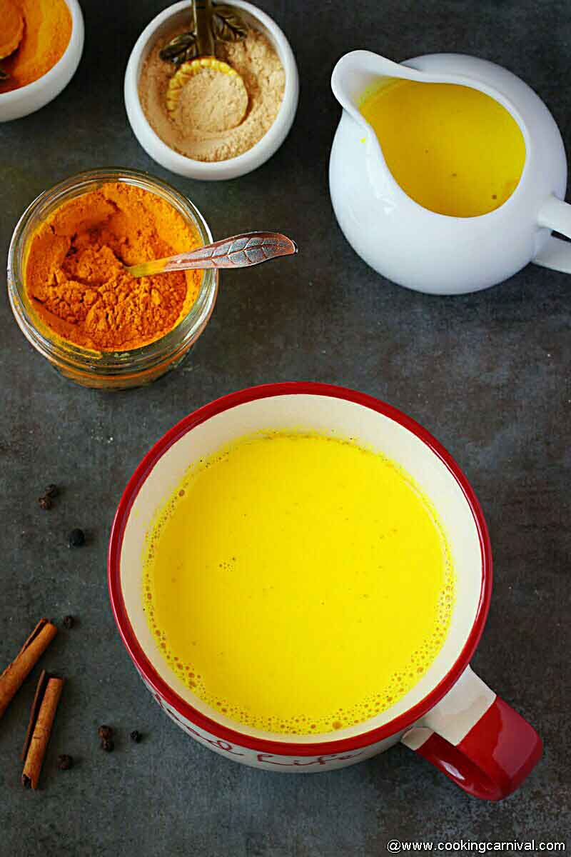 Golden milk in big wide mouth mug, turmeric, dry ginger powder on the side