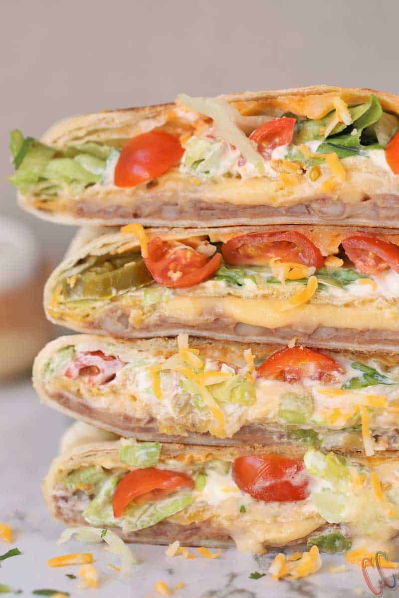 Vegetarian Homemade Crunchwrap Supreme Recipe - Refried beans, cheese sauce, crunchy tostadas, sour cream, chopped lettuce, diced tomatoes, Jalapenos and shredded cheese all wrapped inside a large burrito tortilla and then pan roasted until perfectly golden brown in color.