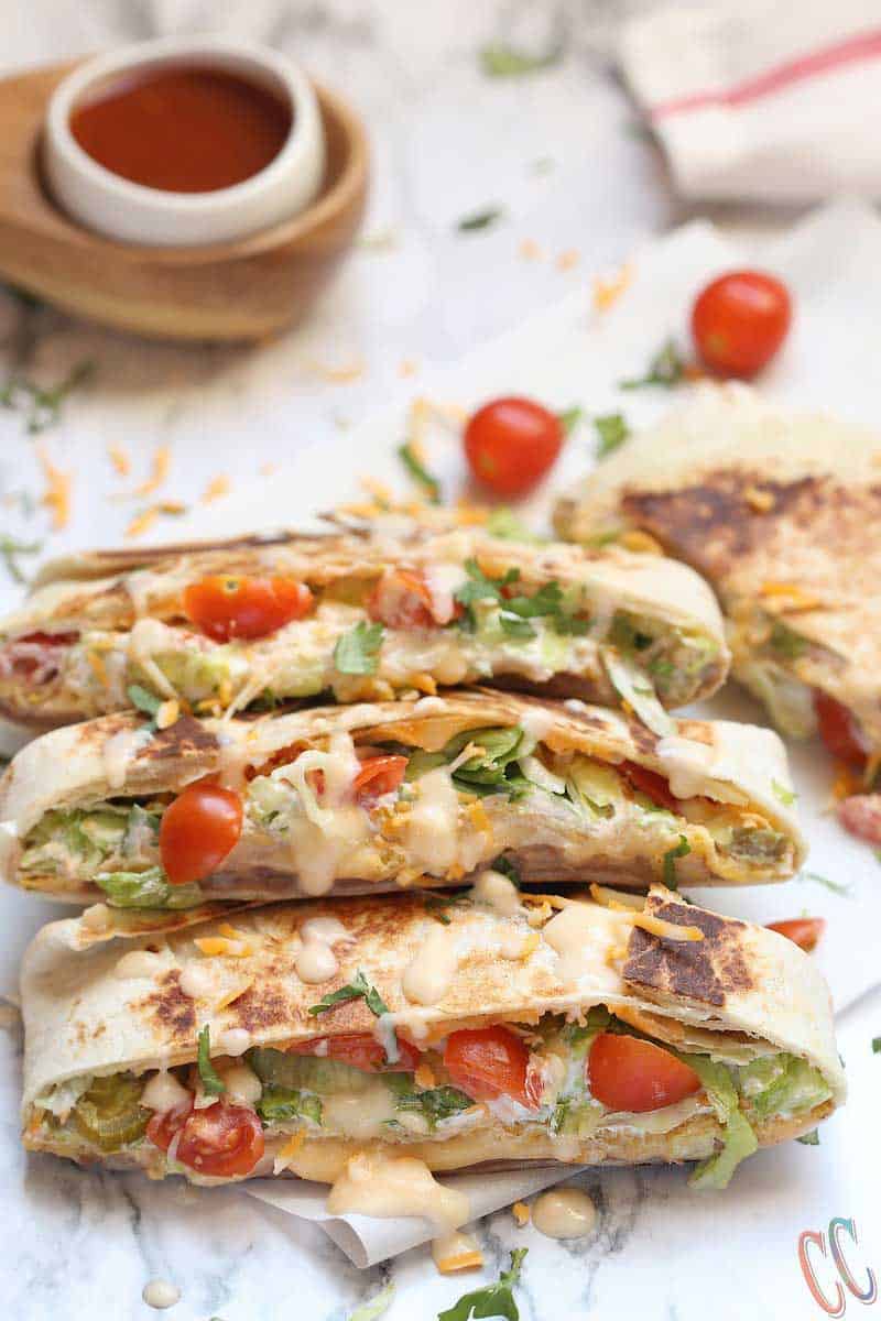 Vegetarian Homemade Crunchwrap Supreme Recipe - Refried beans, cheese sauce, crunchy tostadas, sour cream, chopped lettuce, diced tomatoes, Jalapenos and shredded cheese all wrapped inside a large burrito tortilla and then pan roasted until perfectly golden brown in color.