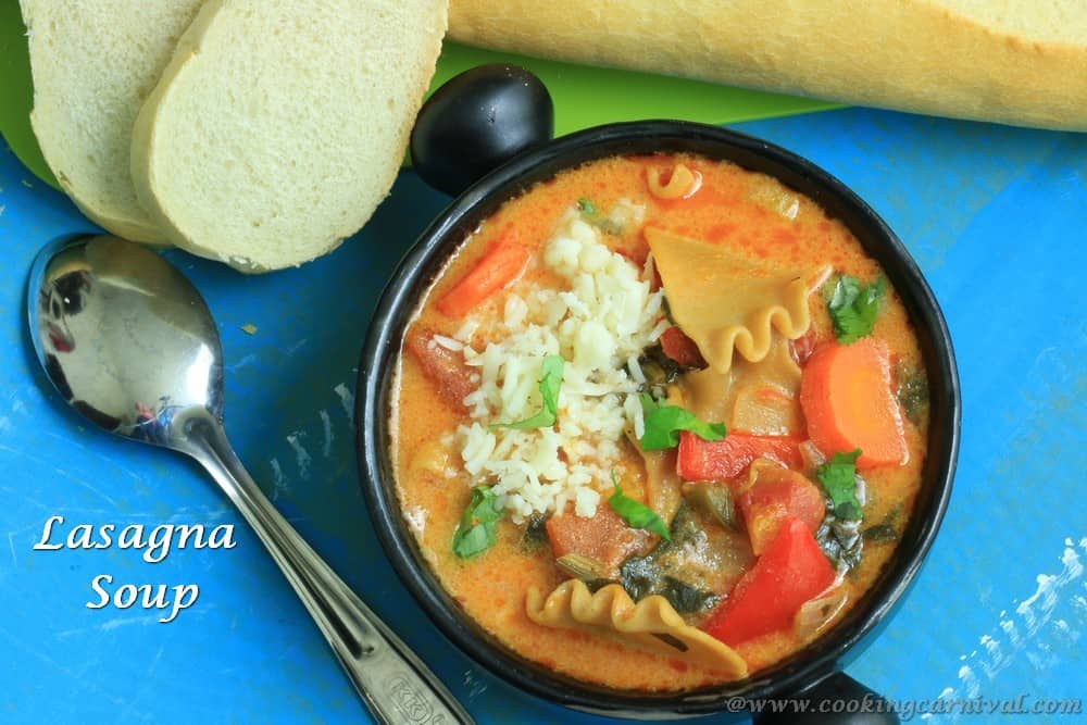 Lasagna Soup in black bowl and crusty bread on the sides