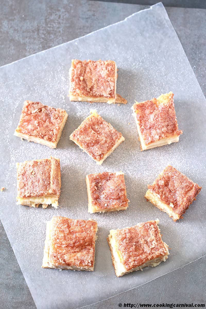 Sopapilla Cheesecake Bars on a black background with parchment paper