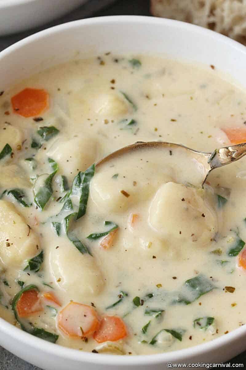 taking creamy soup from the white bowl with copper spoon