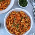 Instant pot Goulash in 3 white serving bowls and parsley on the side