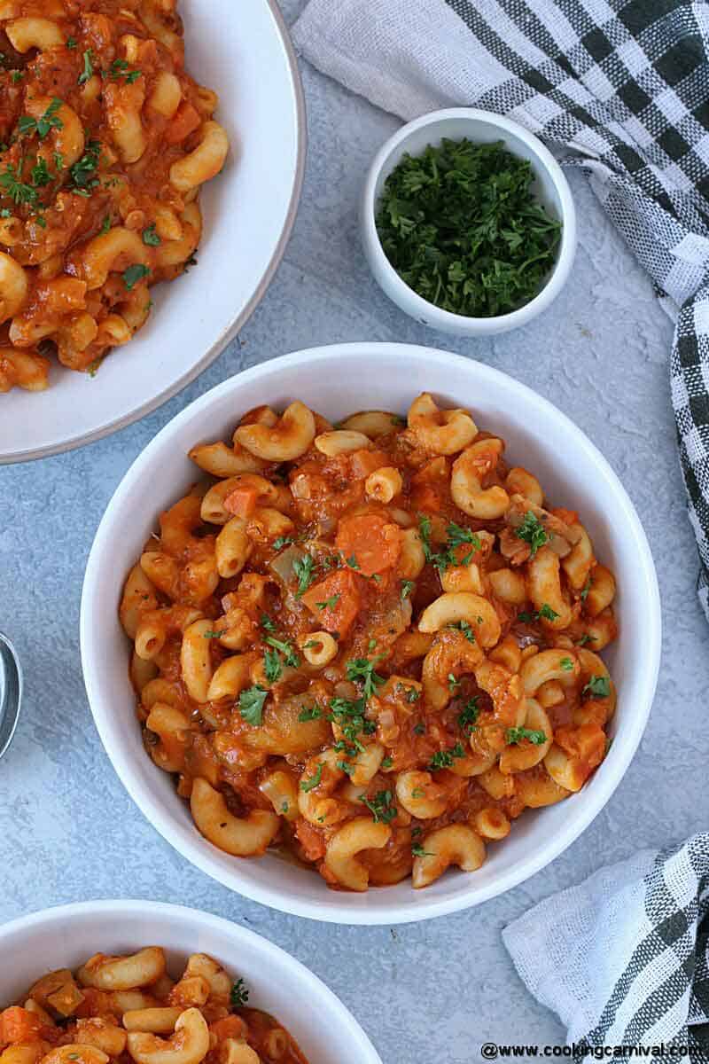 Instant pot Goulash in 3 white serving bowls and parsley on the side