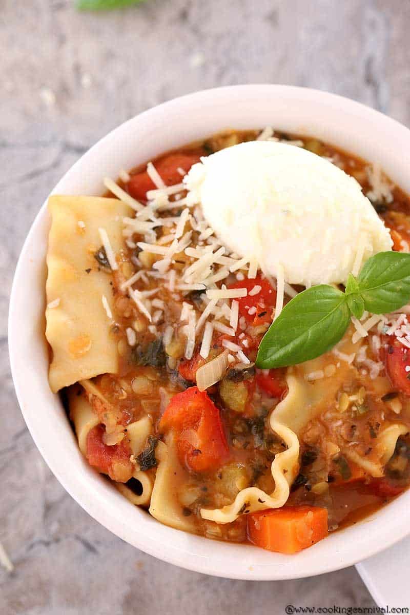 Lasagna Soup in a white bowl with Parmesan cheese, basil and ricotta