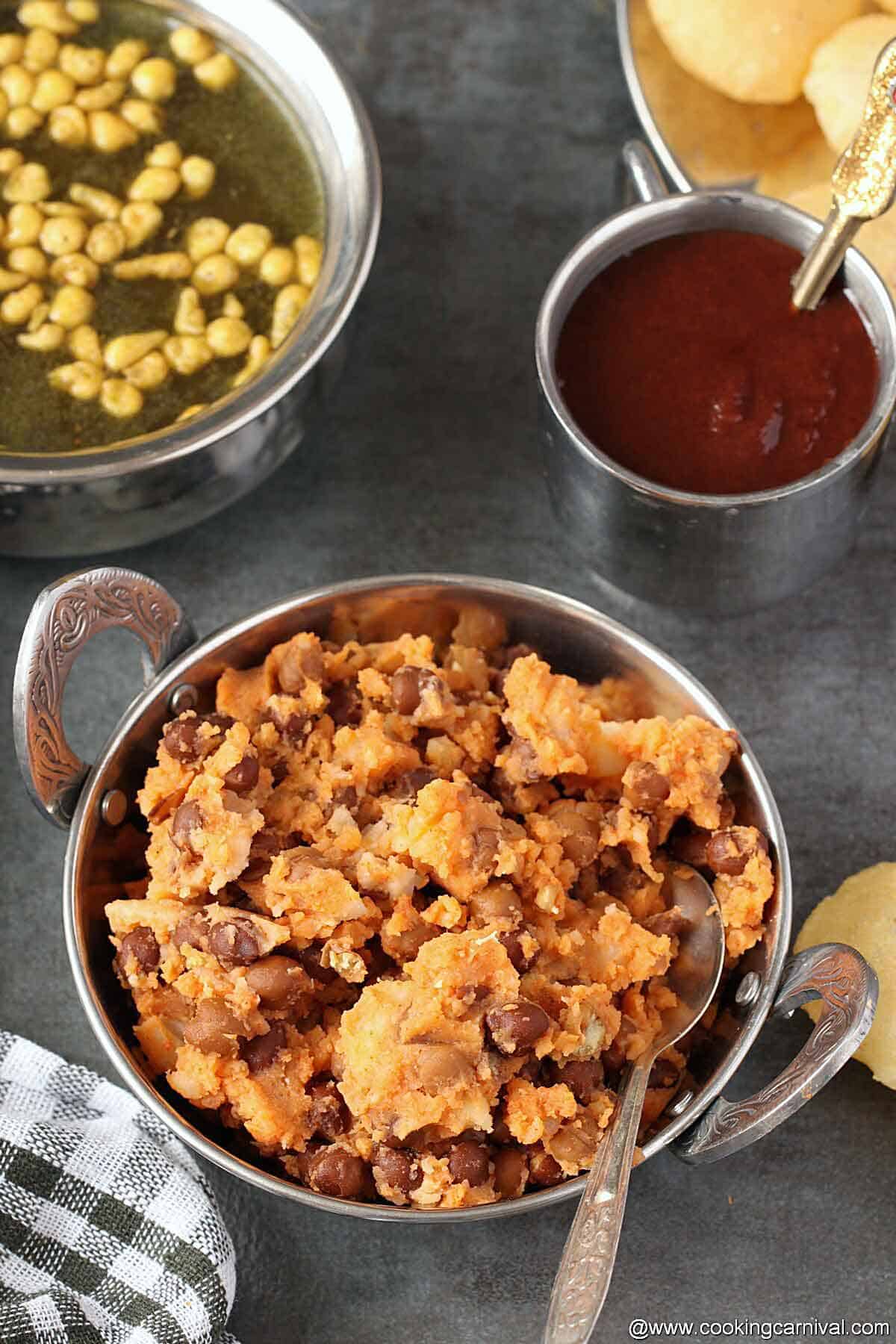 Pani puri masala, spiced water, sweet chutney and puri on a black tile