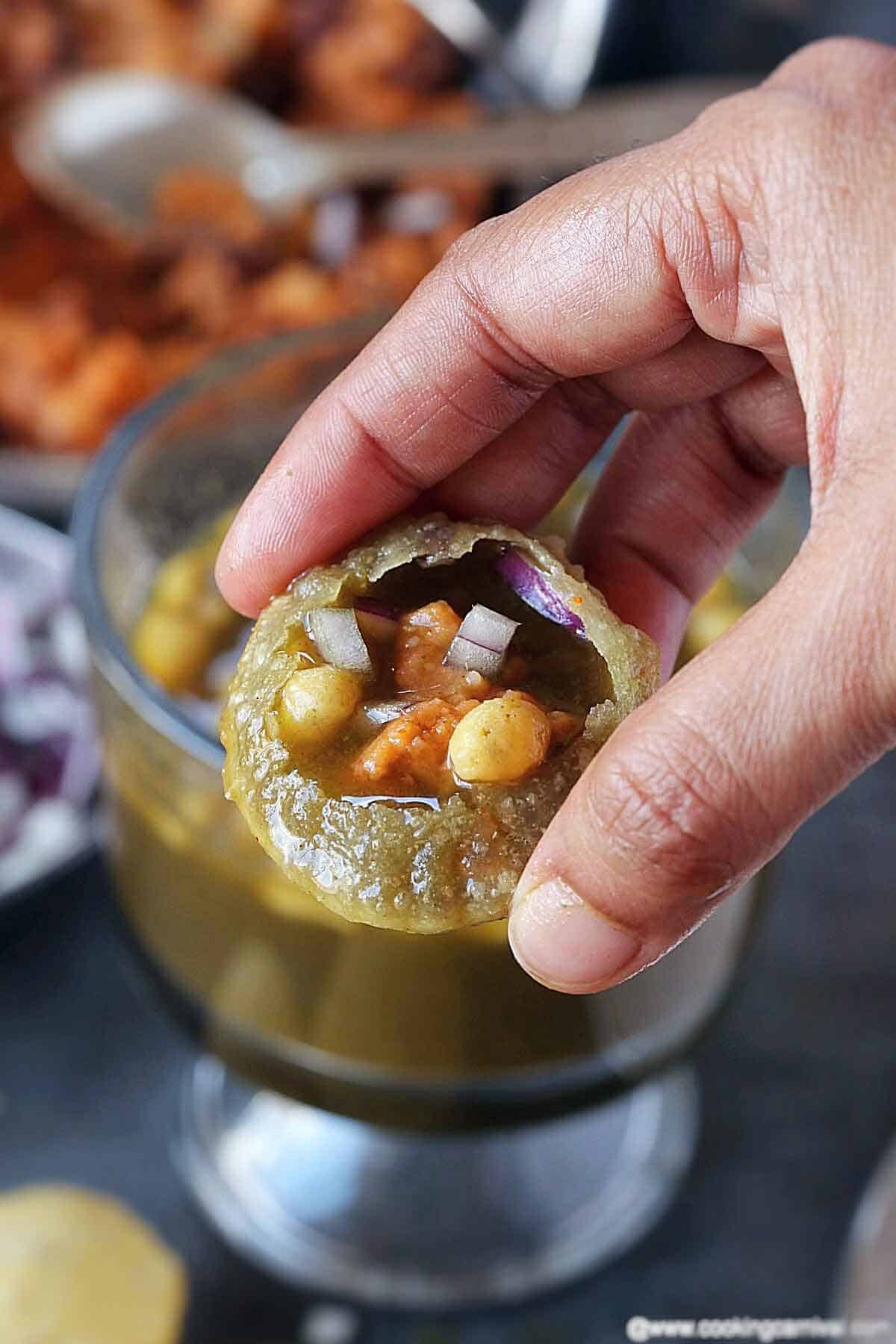 Holding pani puri with stuffing and teekha mitha pani in hand