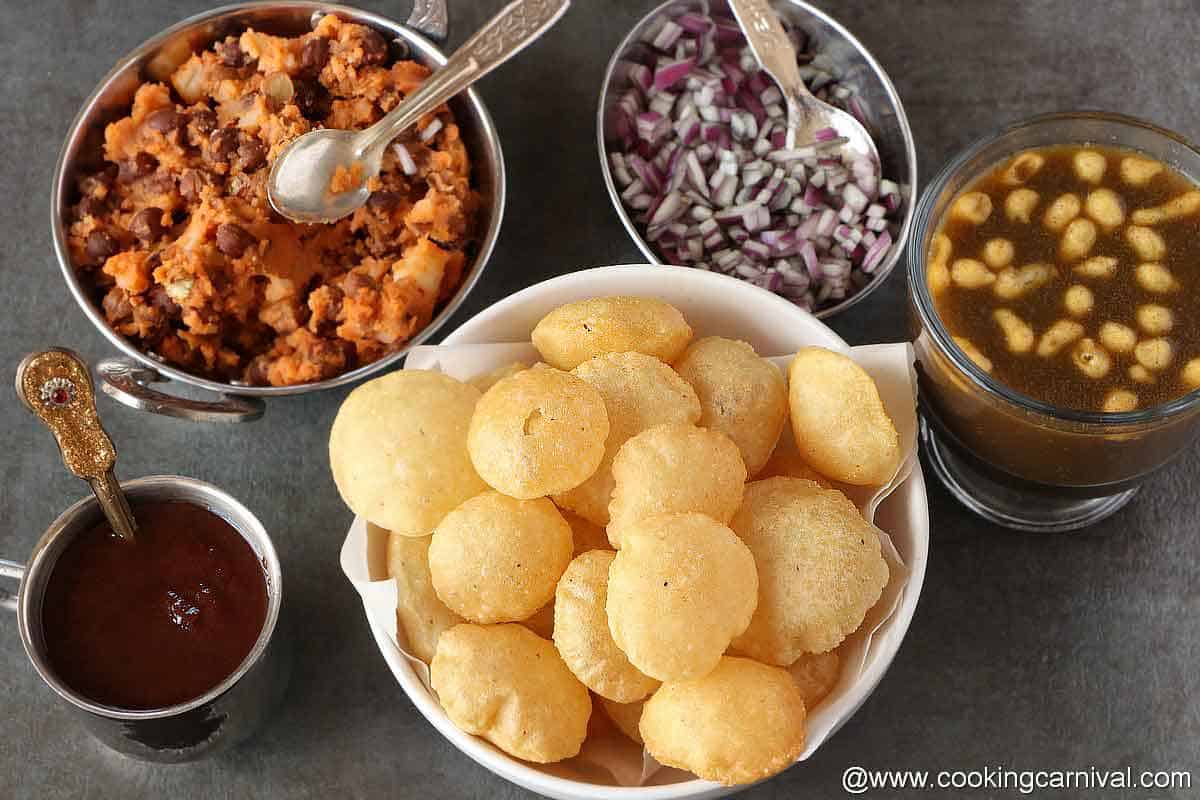 Puri, sweetchutney, stuffing, chopped onion, teekha pani on a black tile