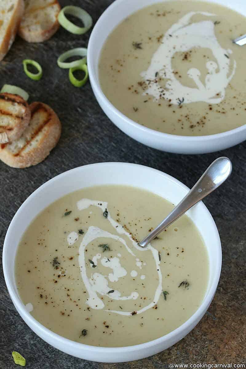 Instant pot potato leek soup in a white bowl with steel spoon, on a carbon black board