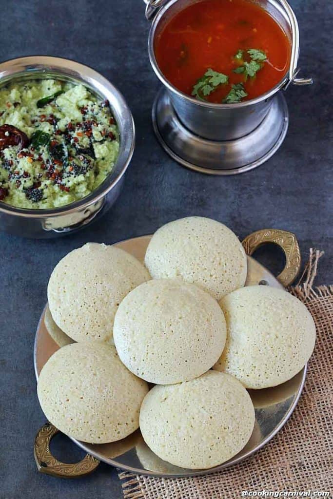 Quinoa idlis in a plate, coconut chutney and tomato rasam on the side