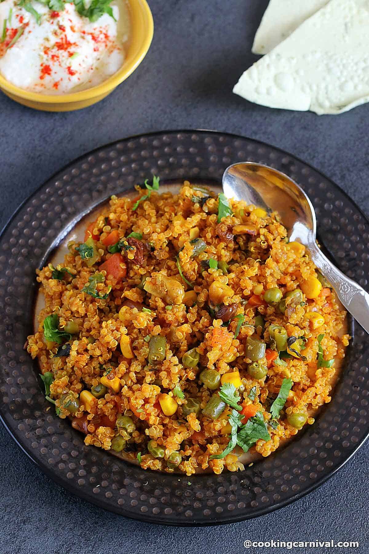 Quinoa pulao on a plate, papad and curd on the side.