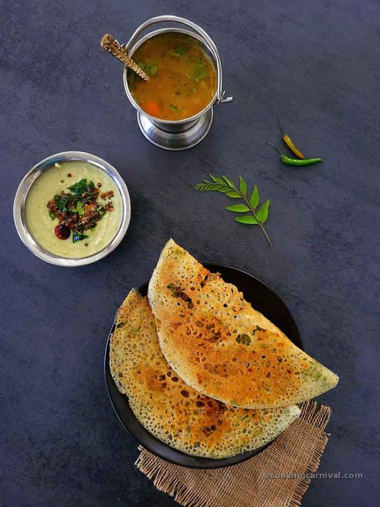 2 Rava dosa in a black plate, coconut chutney and sambar on the side