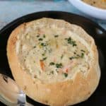 Homemade Bread bowl served with broccoli cheese soup on a black plate