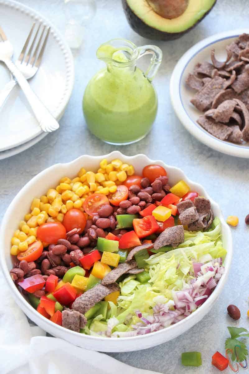 Southwest Salad - Bursting with small kidney beans, corn, bell peppers, cherry tomatoes, sweet corn, cheese, crispy lettuce, onions and bathed in Creamy-smooth Avocado Dressing, topped with blue corn tortilla chips. A super simple and classic salad that can be eaten in any season, be it summer, winter, spring or fall!