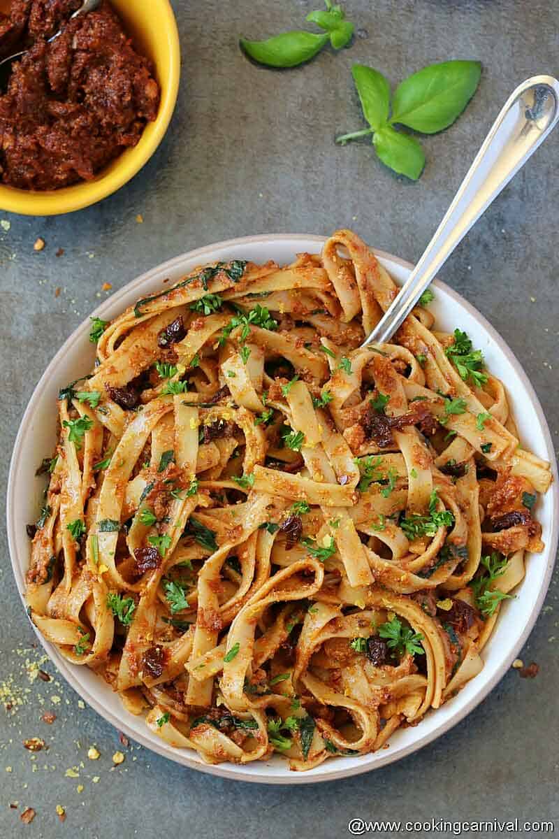 sun dried tomato pesto pasta in white bowl with fork