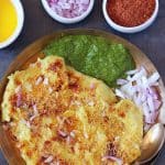 Surti locho in kansa plate, green chutney and onion on the sides