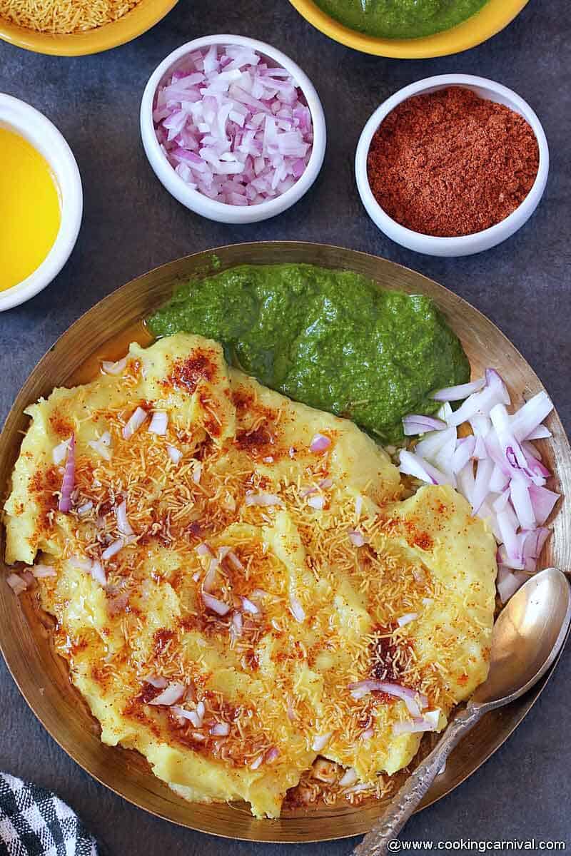 Surti locho in kansa plate, green chutney and onion on the sides