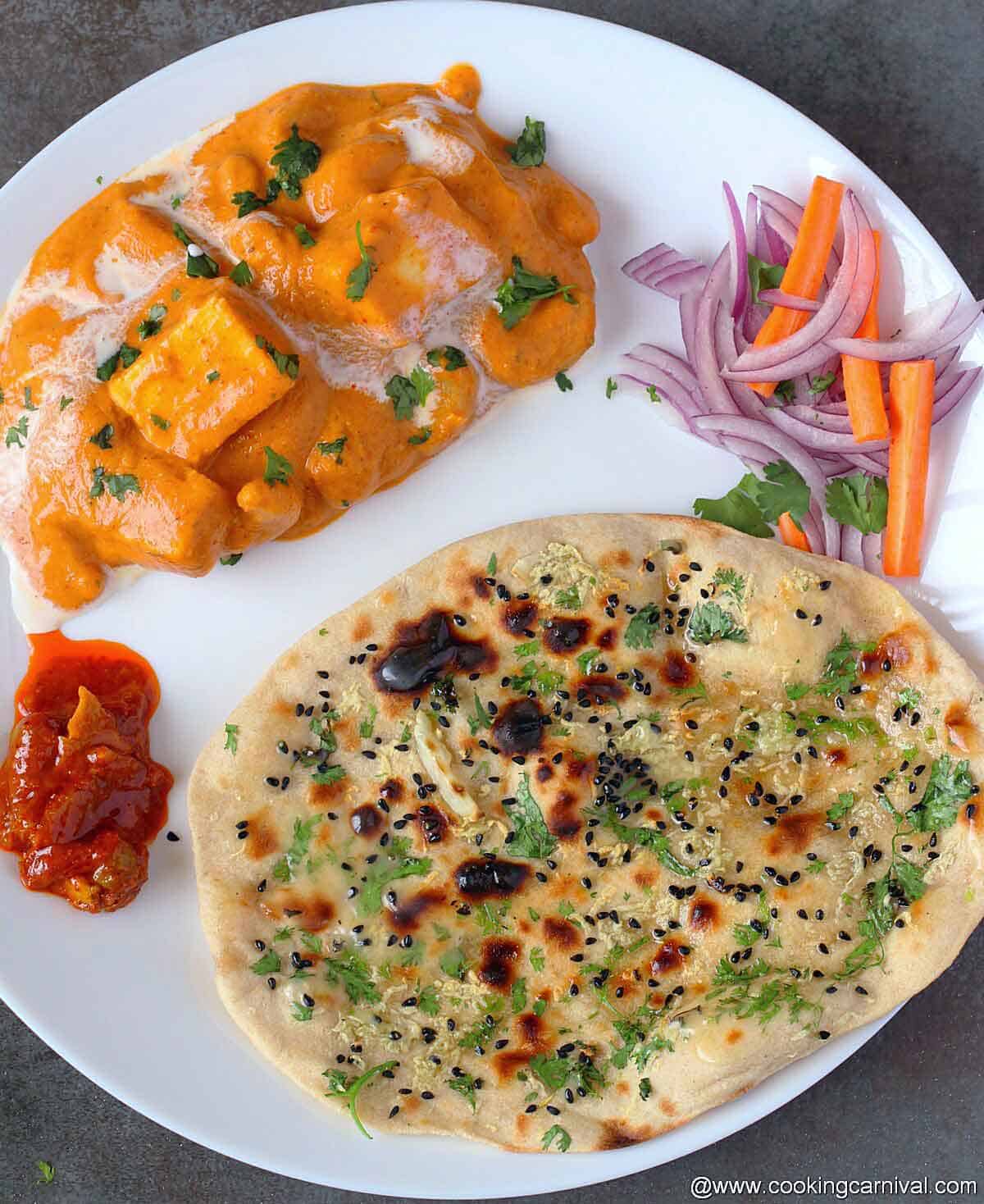 Tandoori garlic roti, kaju paneer, salad and pickle on white plate