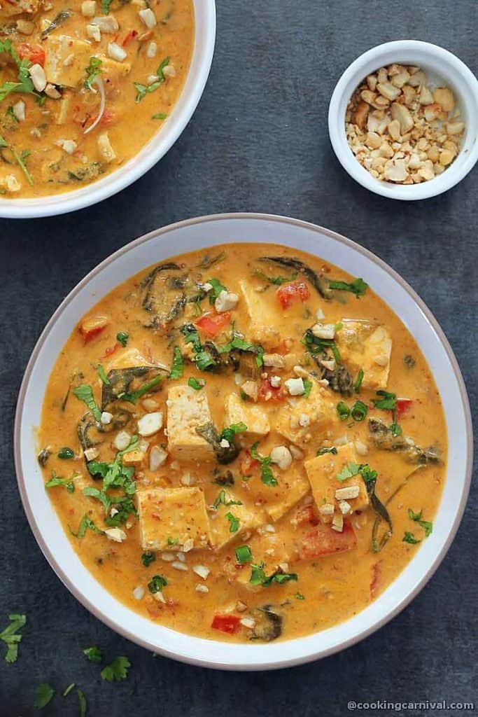 thai peanut curry, garnished with peanuts, spring onion and cilantro, served in a white bowl