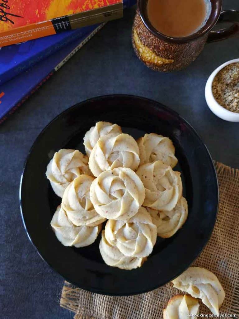 Thandai Melting Moment Butter Cookies in a black plate, chai and books on the side