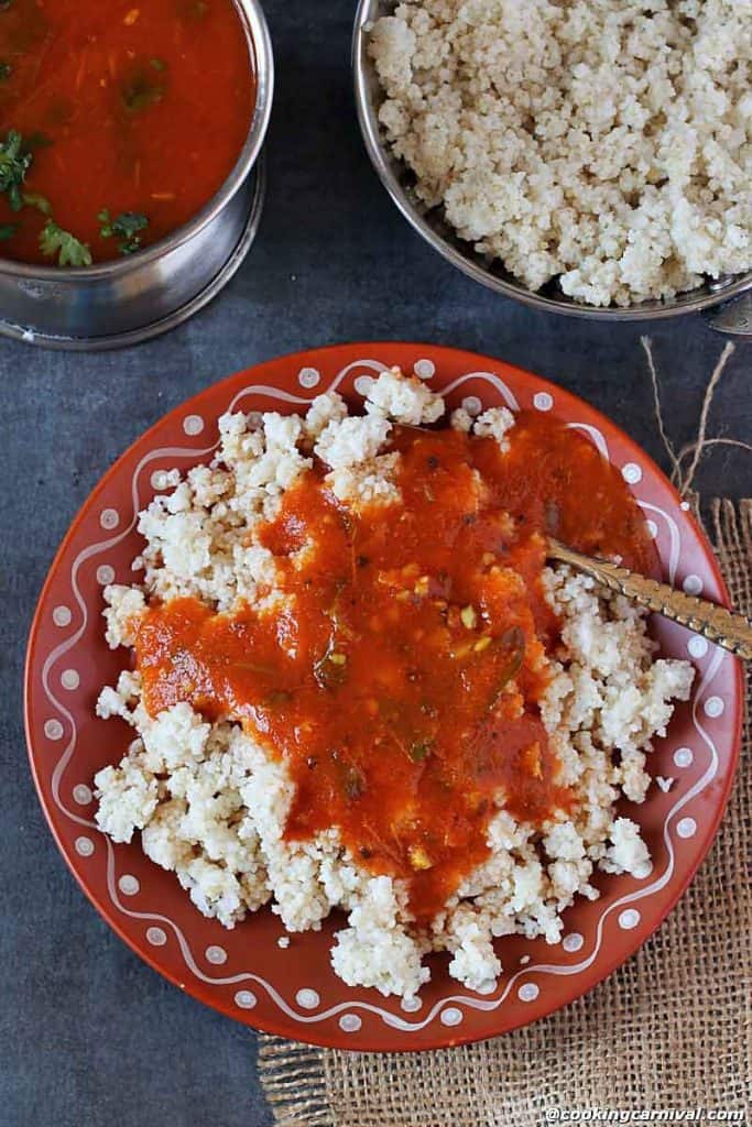 Tomato Rasam qith barnyrd millet on a plate with spoon