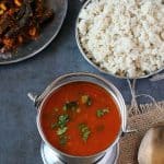 Tomato rasam in steel pot, barnyard millet on the sides