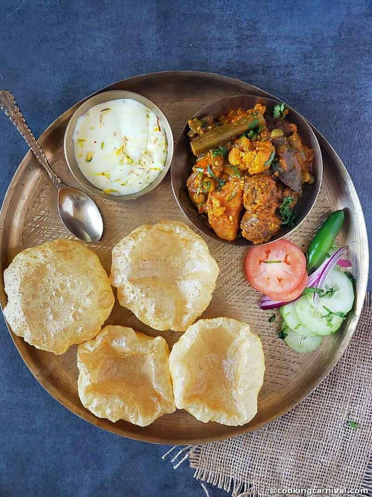 A traditional kathiyadi thali with Undhiyu, poori, shrikhand and salad