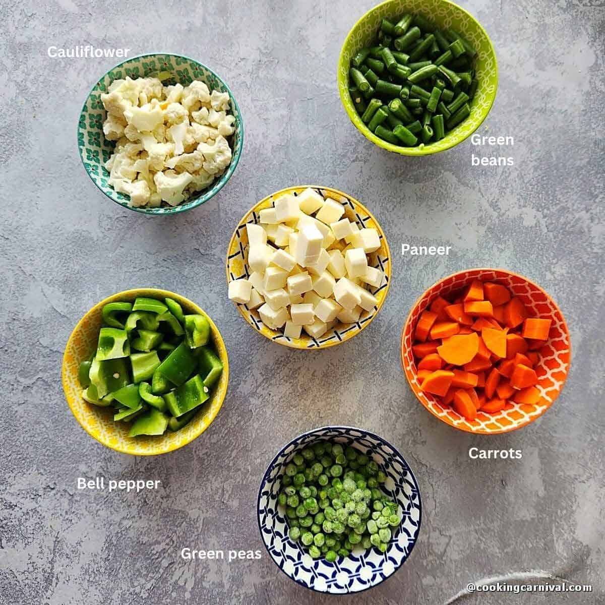 green beans, bell pepper, cauliflower, green peas, carrots and panner on a tile.