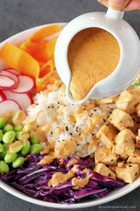 drizzling chipotle tahini sauce over vegan poke bowl