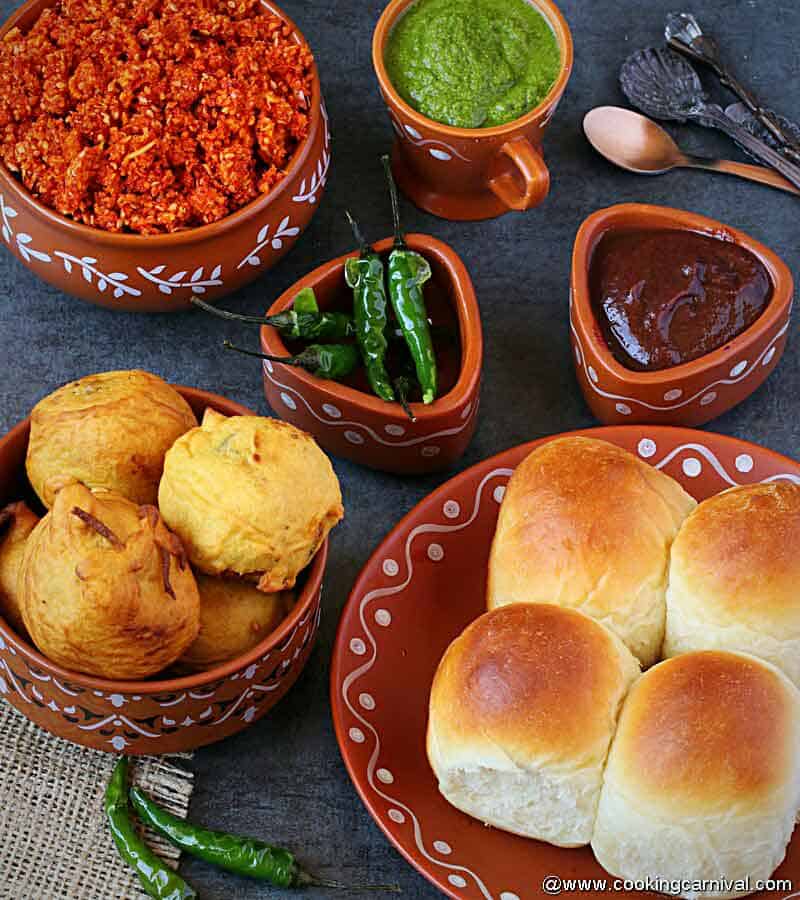 vada, bun, green fried chilies, sweet chutney, green chutney, dry garlic chutney served in a indian traditional serving ware