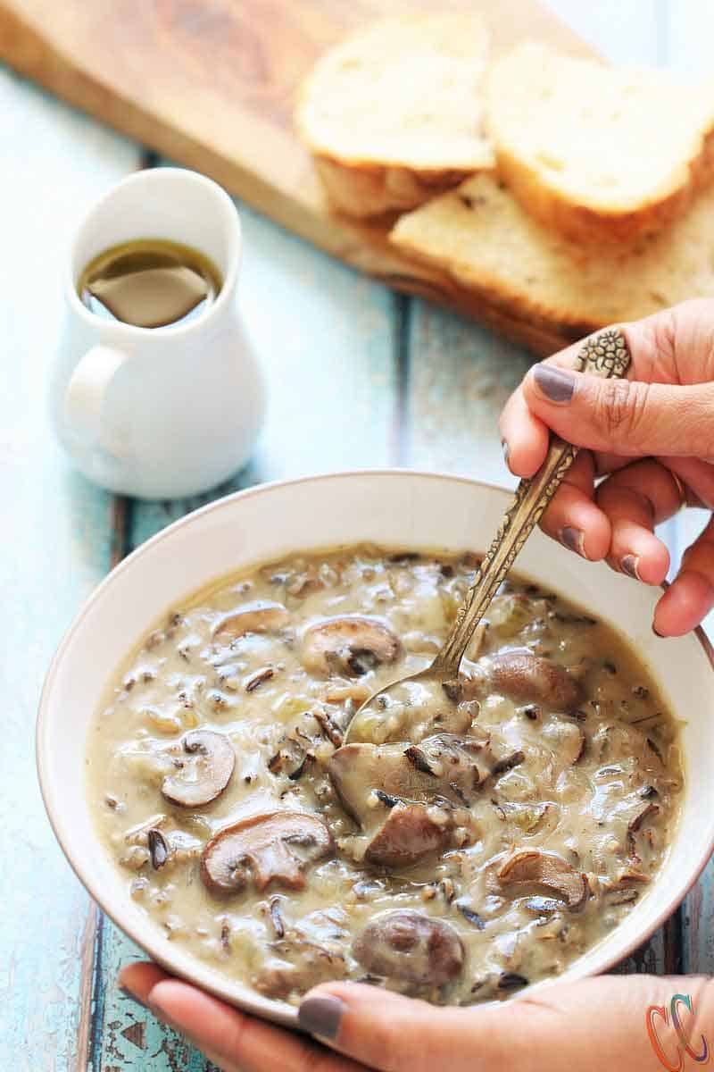 Picture of Wild rice soup in a bowl and eating it with silver spoon.