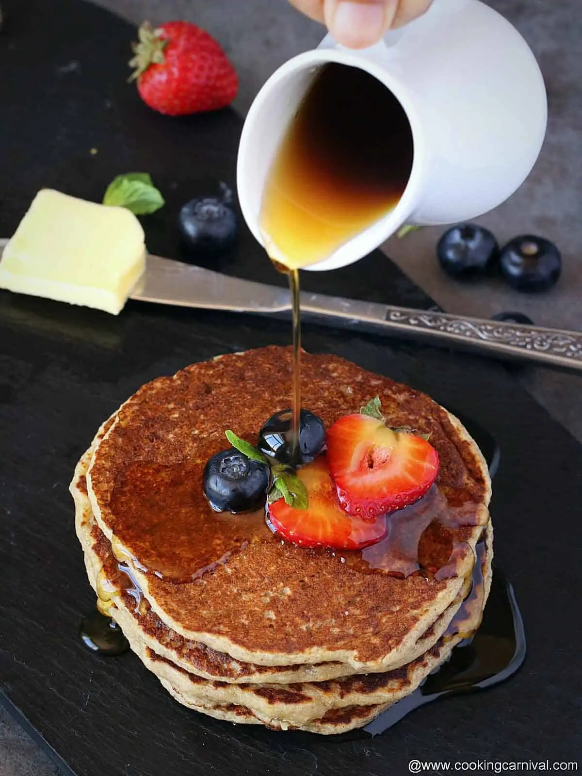 Pouring maple syrup over pancakes