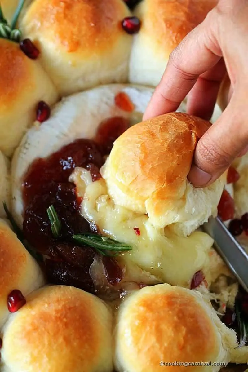 Dipping bread in baked brie cheese