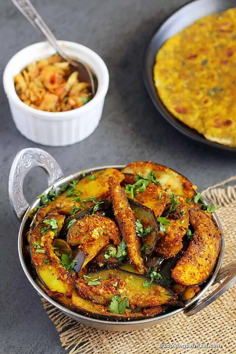 Brinjal Fry in a steel bowl, kachumber and thepla on the side