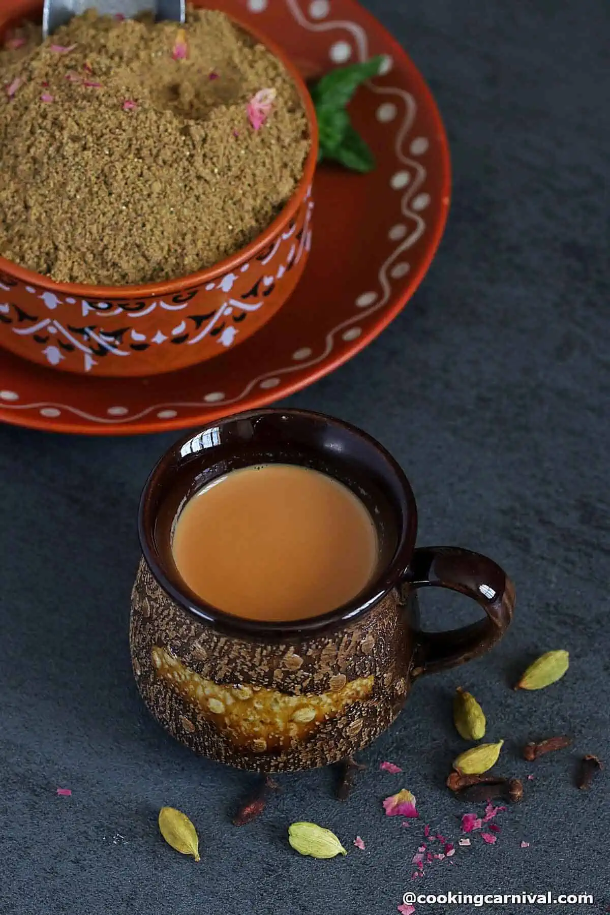 Indian masala tea in a cup, chai spice mix on the side.