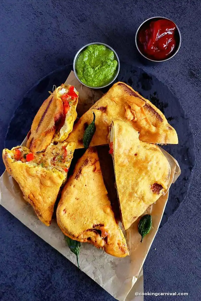 Cheese Chilli Bread Pakora with green chutney and tomato ketchup on a black cheese board.