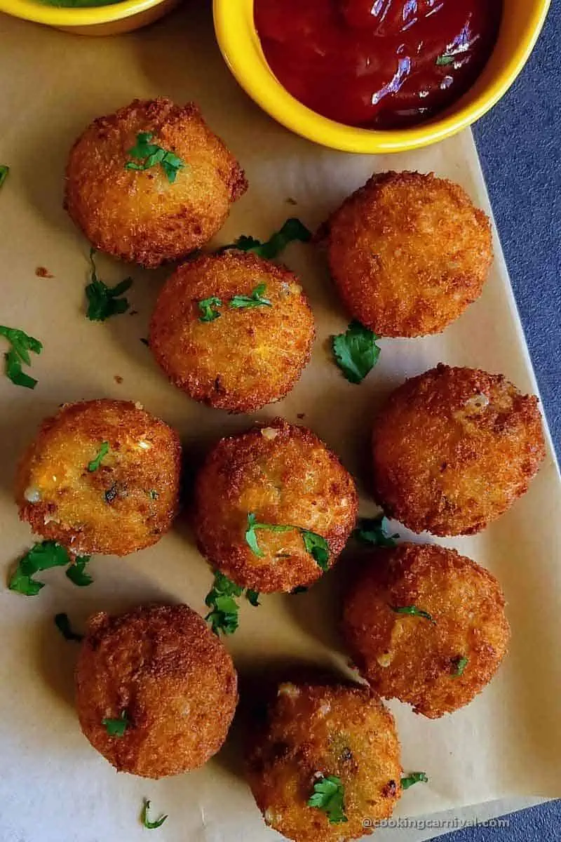 Cheese corn balls on paper with ketchup and green chutney